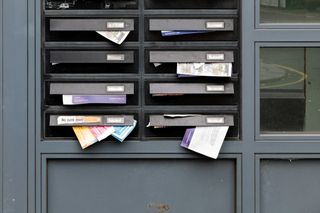 A wall of numbered metal mailboxes with small locks lined up in a postal room.