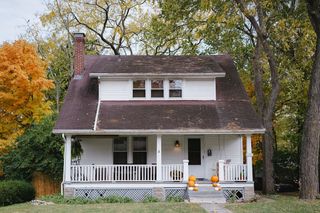 A closed residential front door framed by a quiet suburban porch in soft daylight.