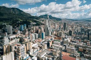 Bogota cityscape with high-rise buildings backed by the Andes mountains under cloudy sky.